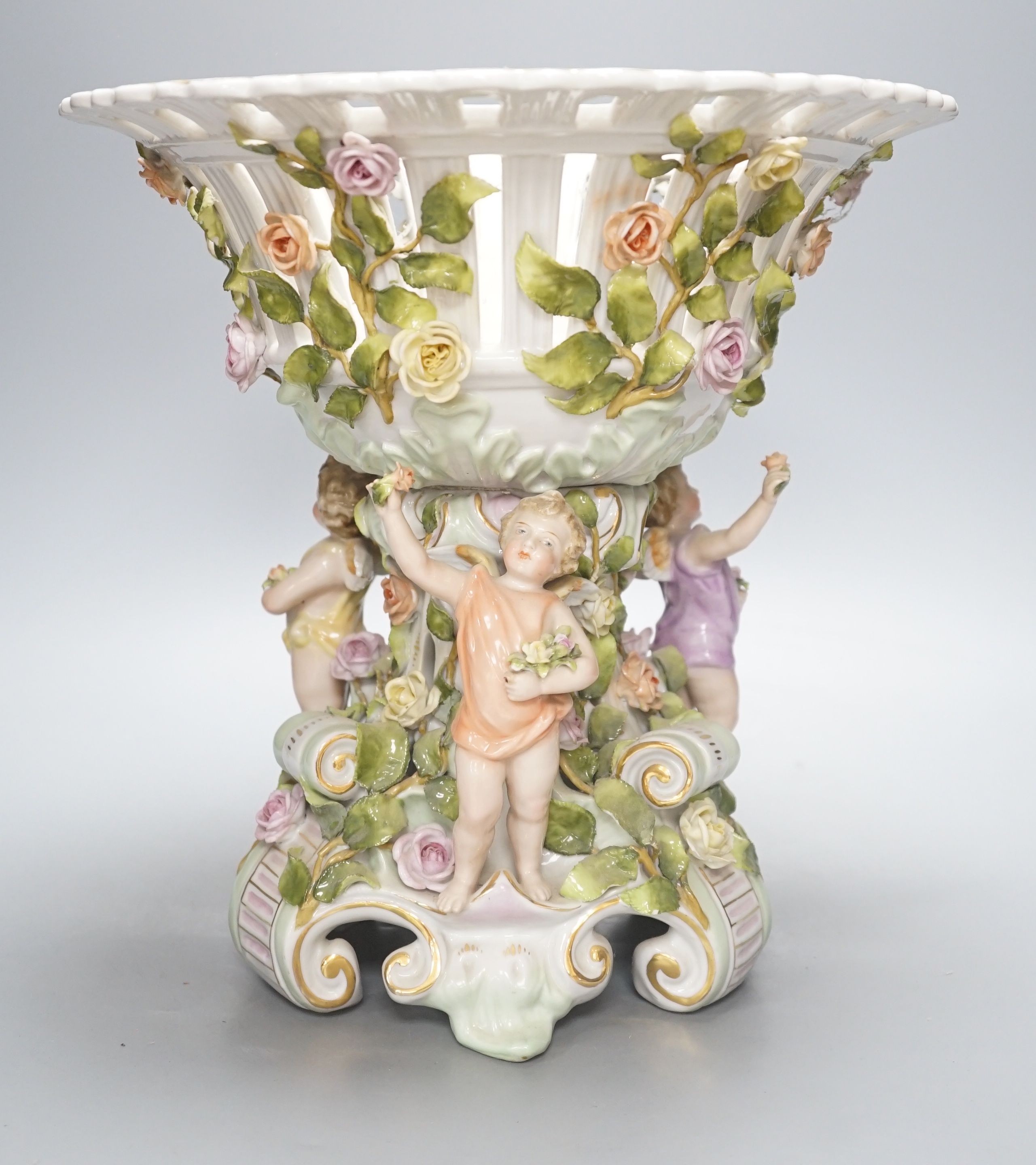 A German porcelain floral encrusted fruit stand, on a figural base, 30cm tall